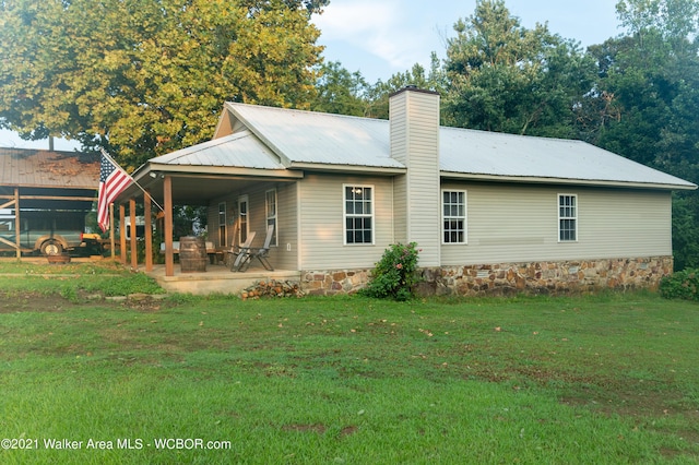 12 Dover Rd, Haleyville, AL 35565 - back of house featuring metal roof, a patio, a chimney, and a lawn