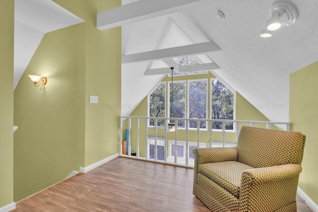 sitting room featuring baseboards, lofted ceiling, wood finished floors, and a textured ceiling