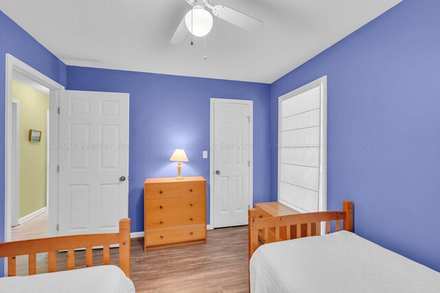 bedroom featuring baseboards, wood finished floors, and a ceiling fan