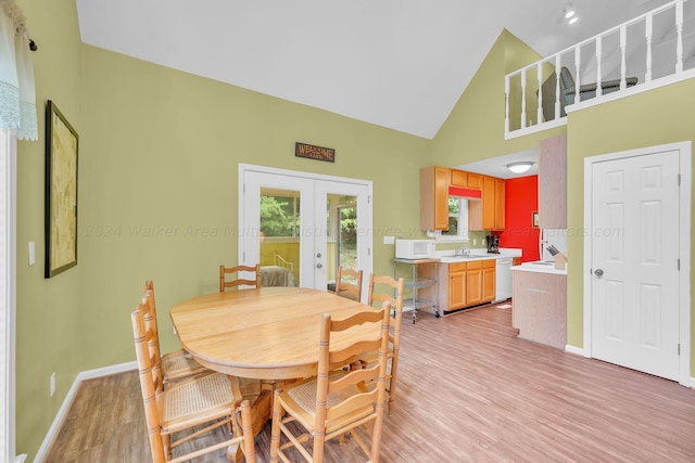 dining space featuring a healthy amount of sunlight, high vaulted ceiling, french doors, and light wood-style floors