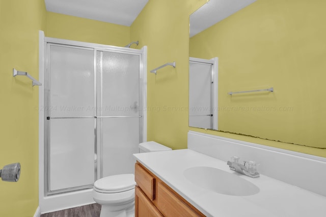 full bathroom with toilet, vanity, a stall shower, and wood finished floors