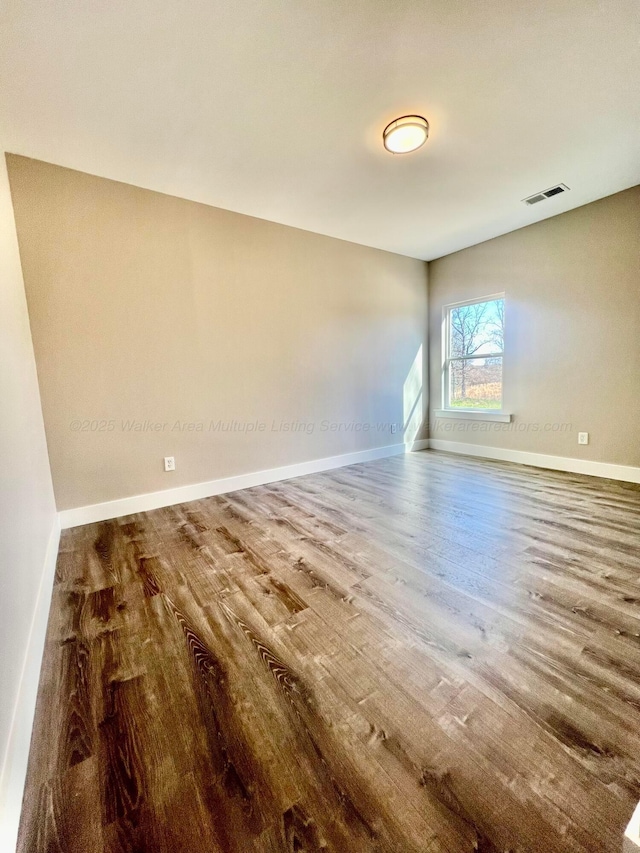 empty room with visible vents, baseboards, and wood finished floors