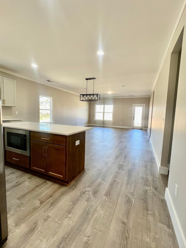 kitchen featuring light countertops, built in microwave, light wood finished floors, and ornamental molding