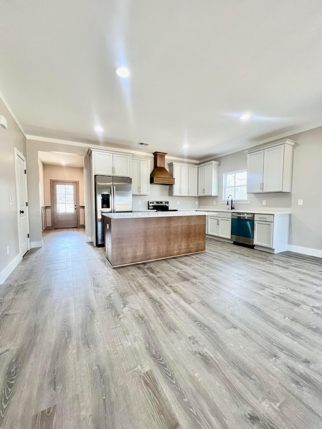 kitchen featuring a kitchen island, stainless steel appliances, light wood finished floors, custom exhaust hood, and light countertops