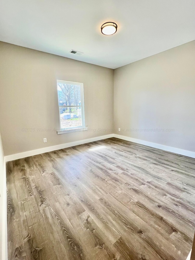 empty room featuring visible vents, baseboards, and wood finished floors