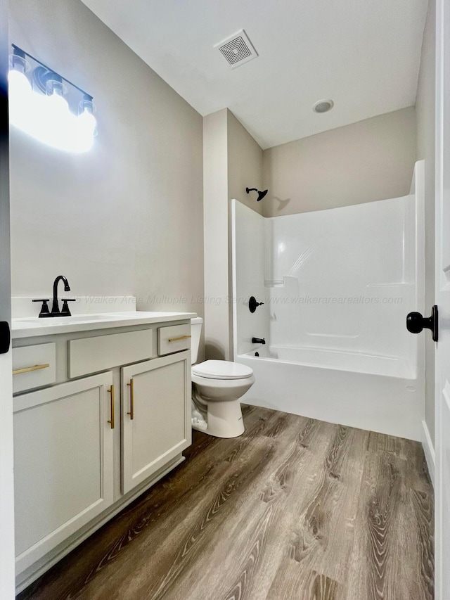 full bathroom with visible vents, toilet, shower / bathtub combination, wood finished floors, and vanity