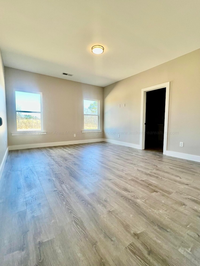 unfurnished room with visible vents, baseboards, and wood finished floors