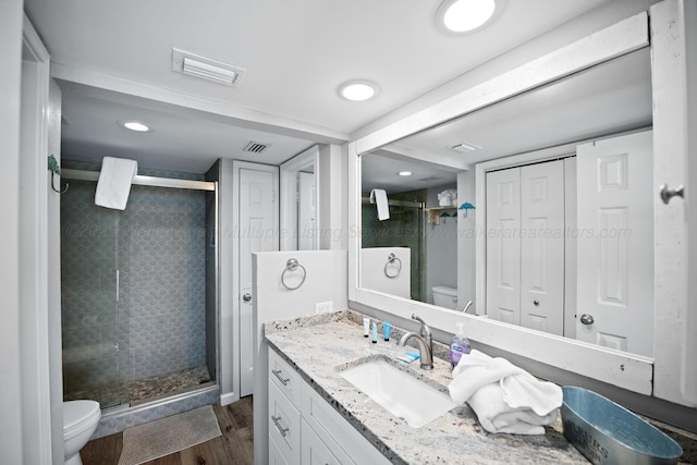 full bath with toilet, a shower stall, vanity, wood finished floors, and recessed lighting