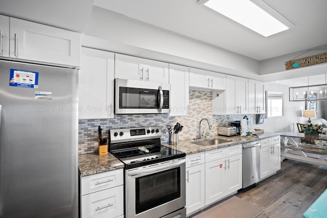 kitchen featuring stainless steel appliances, a sink, dark wood-style flooring, white cabinetry, and light stone countertops