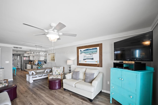 living room featuring wood finished floors, ceiling fan, crown molding, and baseboards