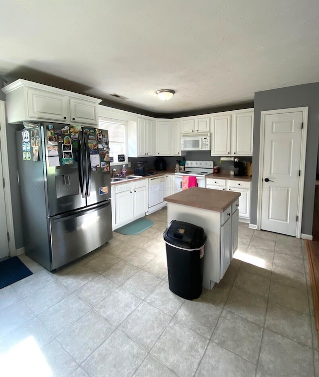 164 County Road 1636, Cullman, AL 35058 - kitchen with white appliances, white cabinets, a kitchen island, and light tile patterned floors