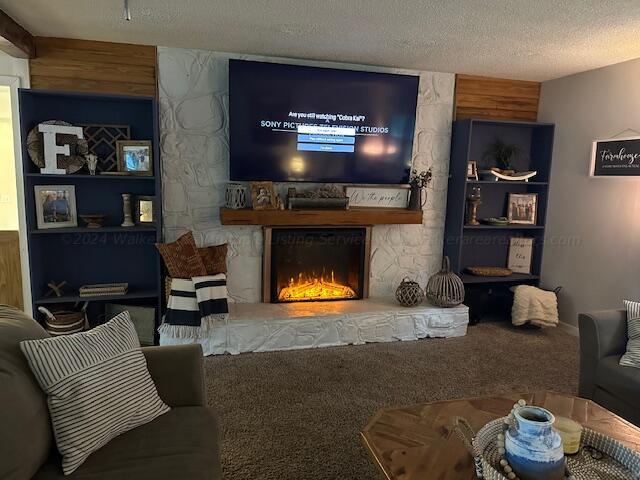 carpeted living room with a stone fireplace and a textured ceiling