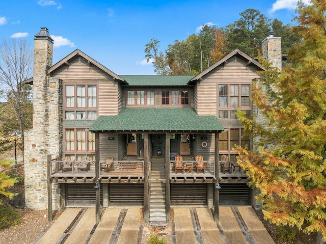 view of front of home with a chimney, a shingled roof, a porch, and an attached garage