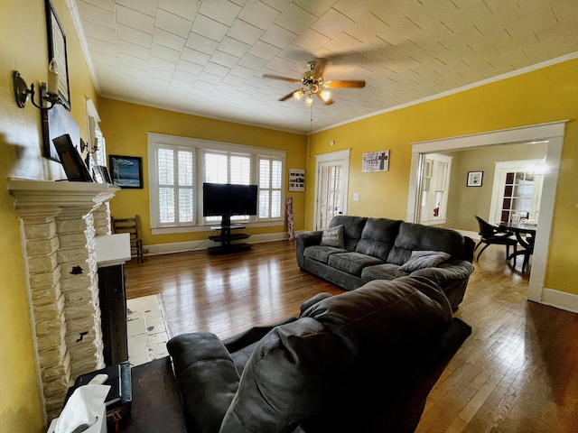 living room with hardwood / wood-style flooring, crown molding, baseboards, and ceiling fan