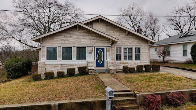 view of front of home with a front lawn, entry steps, and stone siding