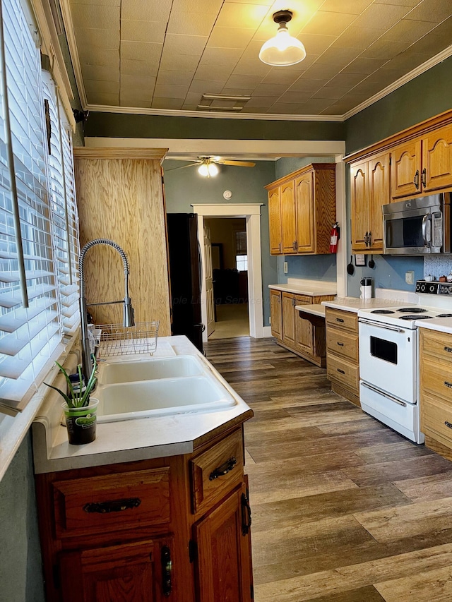 kitchen with crown molding, freestanding refrigerator, stainless steel microwave, a sink, and white electric range
