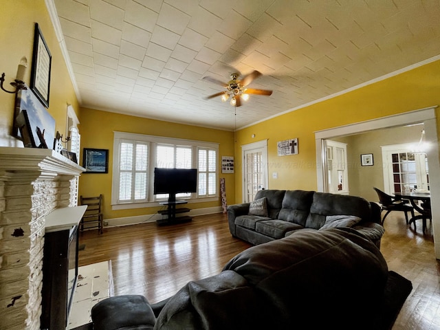 living room with baseboards, ceiling fan, wood finished floors, and crown molding