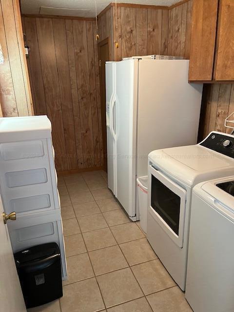915 County Highway 4, Winfield, AL 35594 - clothes washing area with cabinet space, wooden walls, washer and clothes dryer, and light tile patterned floors