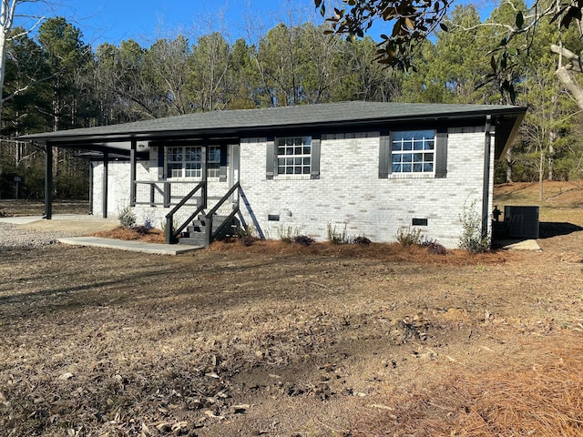 view of front facade featuring brick siding, a shingled roof, and crawl space