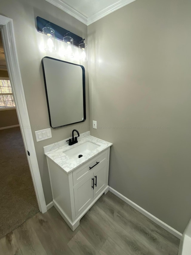 bathroom with baseboards, crown molding, wood finished floors, and vanity