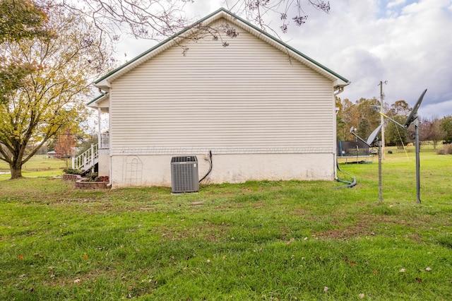 view of property exterior with central AC unit, a trampoline, and a yard