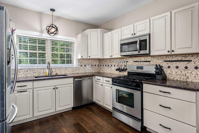 kitchen with pendant lighting, sink, white cabinetry, dark stone countertops, and stainless steel appliances