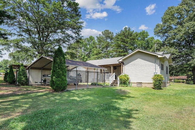 back of property with a lawn and a carport