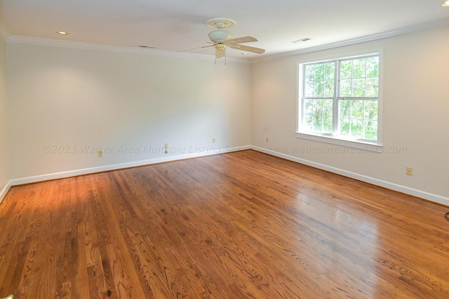 empty room with crown molding, baseboards, visible vents, a ceiling fan, and wood finished floors