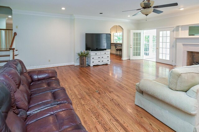 living area featuring baseboards, wood finished floors, ceiling fan, and ornamental molding