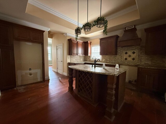 1068 Old Zion Loop, Nauvoo, AL 35578 - kitchen with custom range hood, a raised ceiling, dark wood-style flooring, tasteful backsplash, and an island with sink