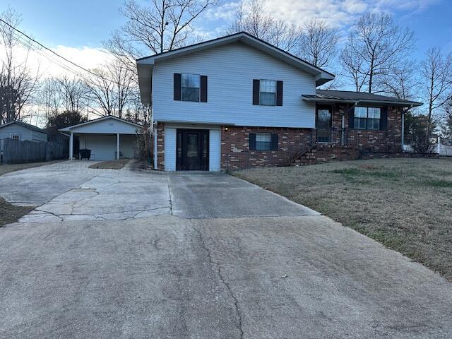 split level home with driveway, a front yard, fence, and brick siding