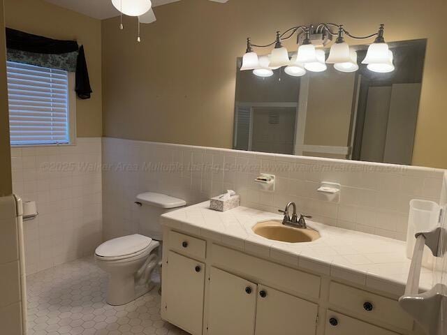 bathroom featuring vanity, tile walls, toilet, tile patterned floors, and a ceiling fan