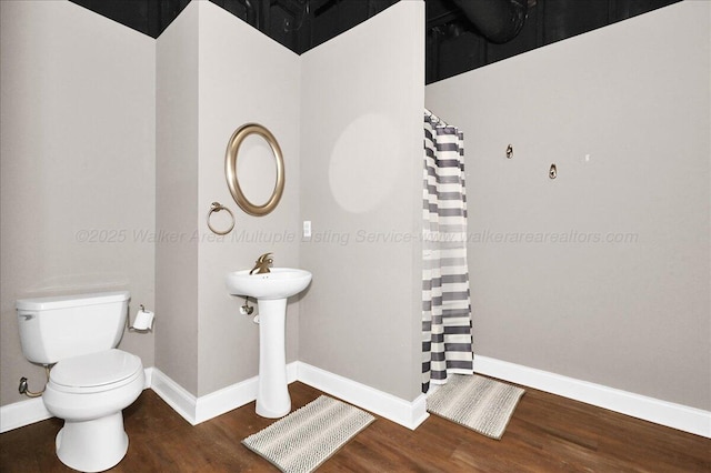 bathroom featuring baseboards, wood finished floors, toilet, and a shower with shower curtain
