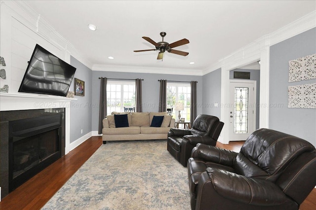 living room featuring baseboards, a fireplace, ornamental molding, wood finished floors, and a ceiling fan