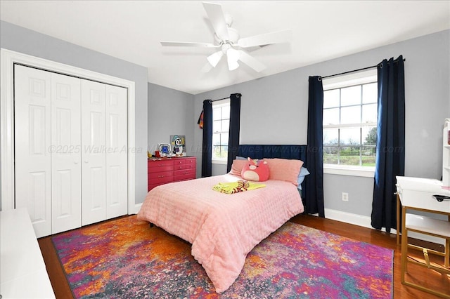bedroom featuring multiple windows, a closet, wood finished floors, and baseboards