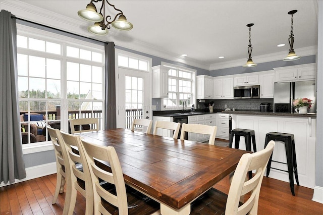 dining area featuring ornamental molding, a chandelier, and dark wood finished floors