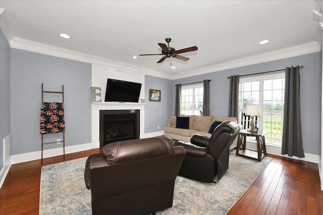 living area featuring wood-type flooring, ornamental molding, a fireplace, and ceiling fan