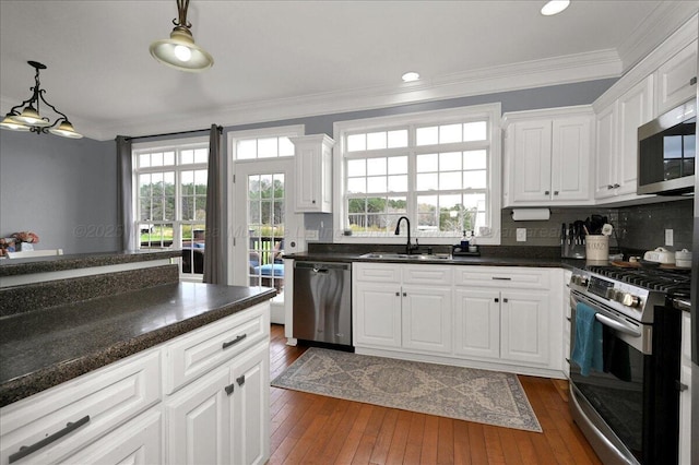 kitchen with a sink, ornamental molding, appliances with stainless steel finishes, and dark wood-type flooring