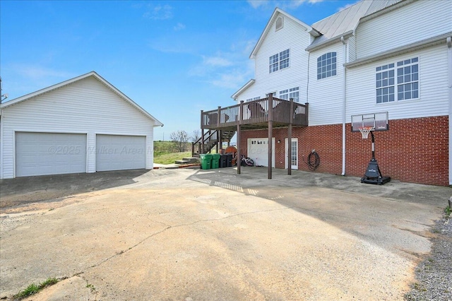 view of side of property featuring a detached garage, a wooden deck, and stairway