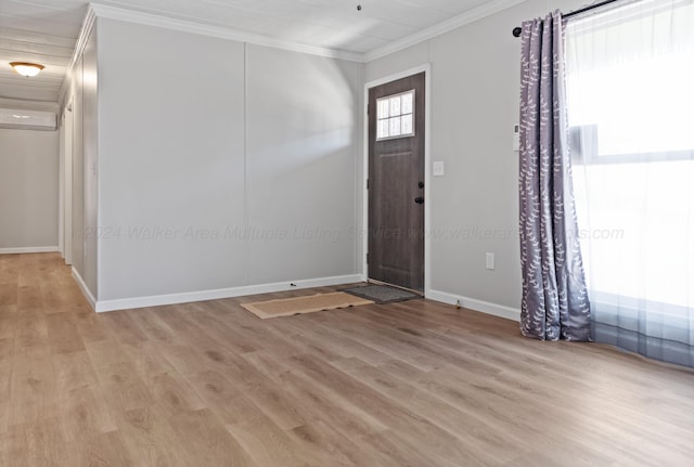 entrance foyer featuring baseboards, a wall mounted AC, crown molding, and light wood-style floors