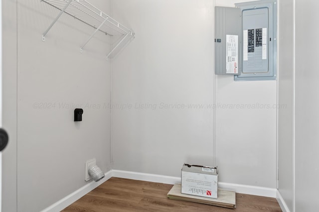 laundry area featuring baseboards, wood finished floors, laundry area, and electric panel