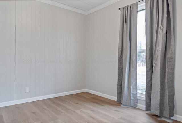 unfurnished room featuring plenty of natural light, crown molding, baseboards, and wood finished floors