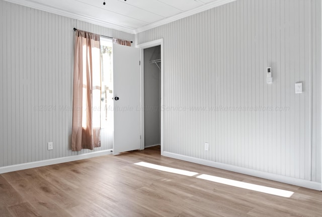 empty room featuring crown molding, baseboards, and wood finished floors