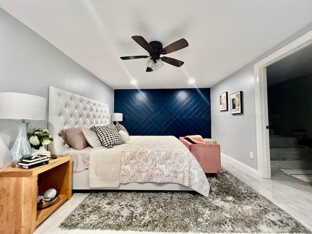 bedroom featuring baseboards, ceiling fan, and an accent wall
