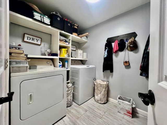 laundry area featuring light wood finished floors, laundry area, baseboards, and washing machine and dryer