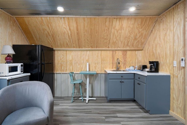 1433 Sipsey Pines Rd, Arley, AL 35540 - kitchen with white microwave, a sink, wooden walls, light wood finished floors, and vaulted ceiling