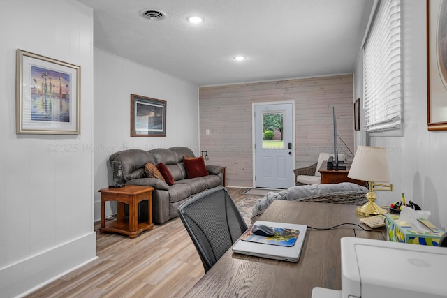 living area with light wood-type flooring, wooden walls, and recessed lighting