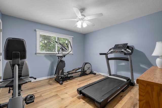 workout room with a ceiling fan, wood finished floors, baseboards, and a textured ceiling