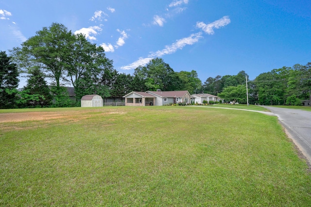 ranch-style home with a shed, a front lawn, and an outbuilding