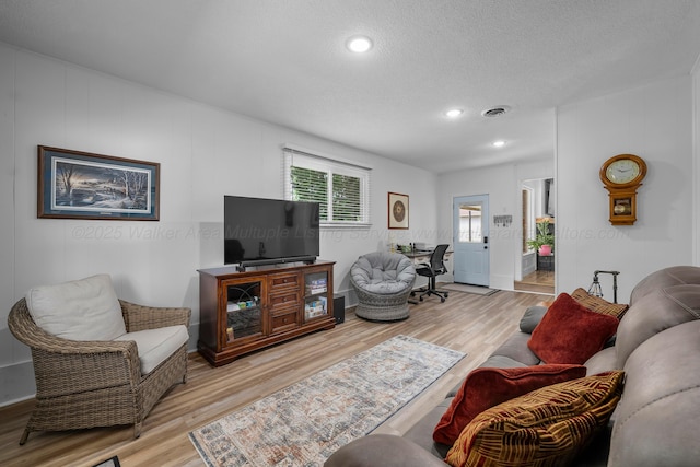living area featuring light wood finished floors, a textured ceiling, recessed lighting, and baseboards